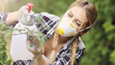 Adult woman spraying plants in garden to protect from diseases